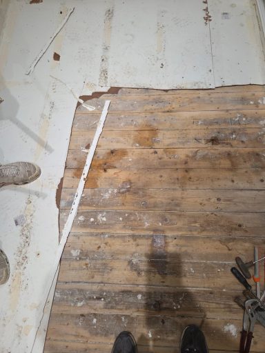 Sol en bois avec des zones abîmées et des traces de nettoyage.